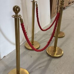 Käytetyt kultaiset kulunohjaustolpat punaisella köydellä